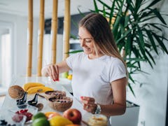 A woman prepares a fruit ice cream bowl at home in her kitchen. 