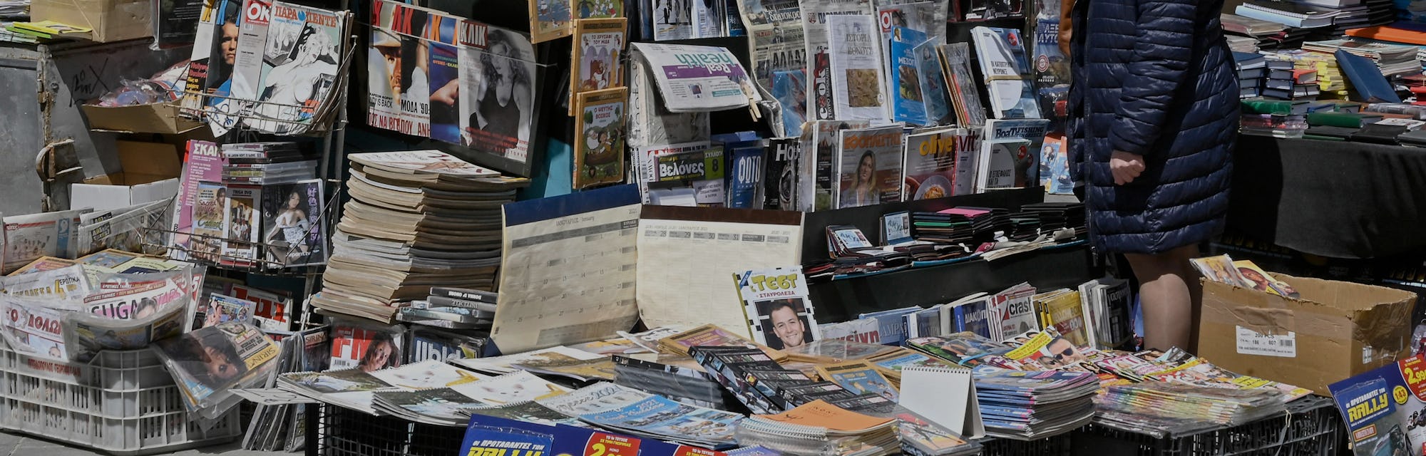 A woman reads newspaper's headlines referring to the killing of a Greek journalist in Athens on Apri...