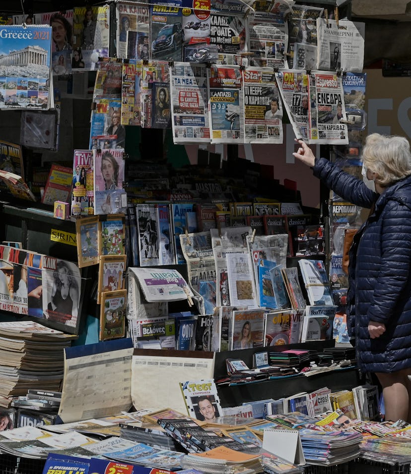 A woman reads newspaper's headlines referring to the killing of a Greek journalist in Athens on Apri...