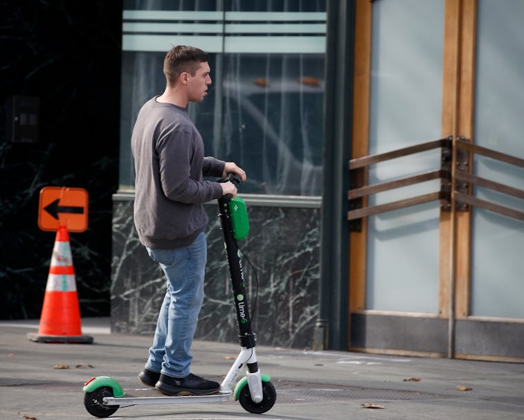 OAKLAND, CA: JANUARY 07: A man rides a Lime scooter on the sidewalk near Broadway in Oakland, Calif....
