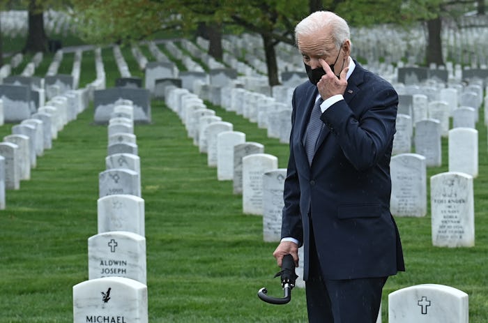 US President Joe Biden wipes his eye as he walks through Arlington National cemetary to honor fallen...