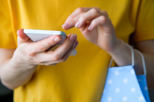 A woman holds a mobile phone to see if Instagram Stories are hidden.