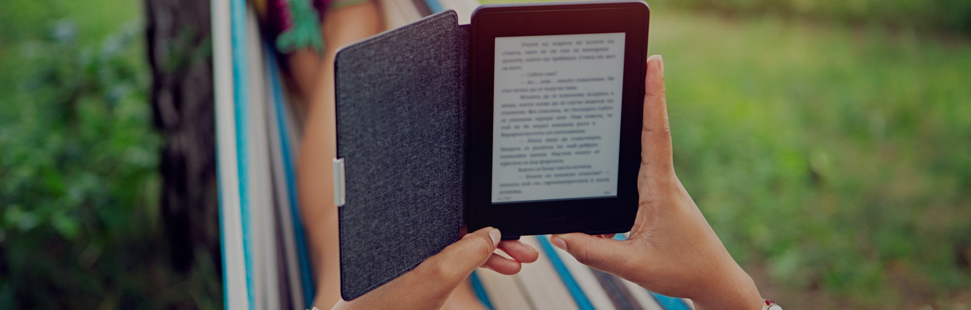 Woman is reading e-book in a hammock /focus point is on the e-book/