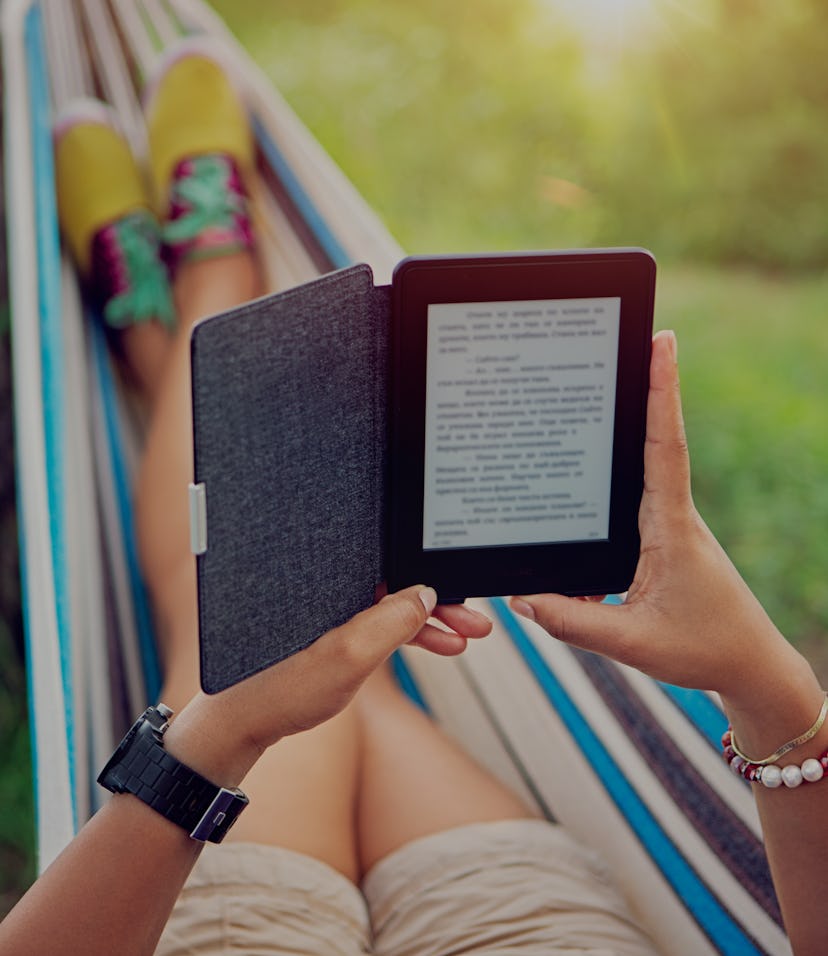 Woman is reading e-book in a hammock /focus point is on the e-book/