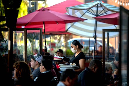 REDLANDS, CA - DECEMBER 05: A server clears a table as patrons dine outdoors at Gloria's Cocina Mexi...