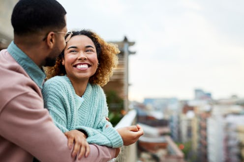 Cheerful Afro woman looking at boyfriend while spending leisure time. Happy couple is at building te...