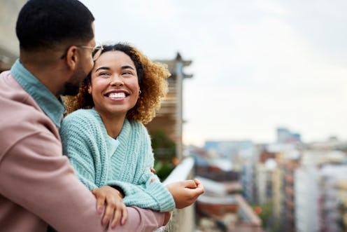 Cheerful Afro woman looking at boyfriend while spending leisure time. Happy couple is at building te...