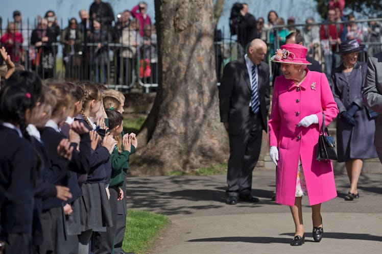 Britain's Queen Elizabeth II is greeted by school children as she arrives to open a bandstand at Ale...