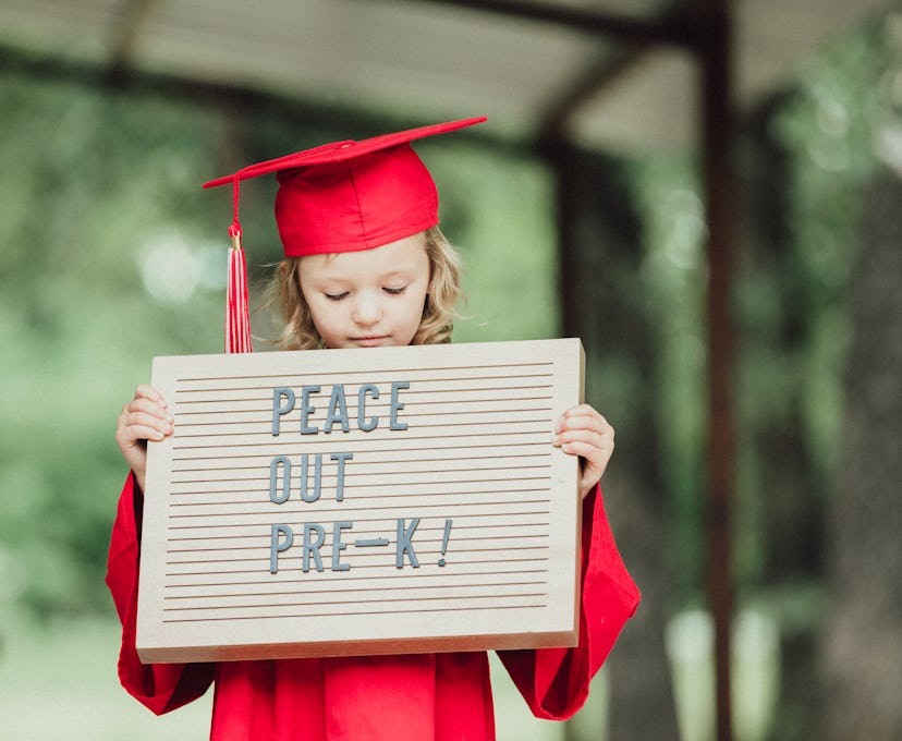 Preschool girl wearing cap and gown and holding sign needs a cute preschool graduation instagram cap...