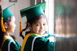 Asian child wearing graduation caps and gown needs a cute preschool graduation instagram caption