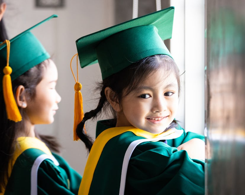 Asian child wearing graduation caps and gown needs a cute preschool graduation instagram caption