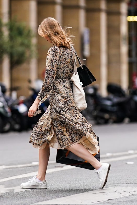 PARIS, FRANCE - JULY 04: A passerby wears a brown flowing dress with animal pattern print, white sne...