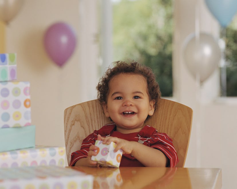 Baby boy smiles and opens present in a story about captions for first birthday photos