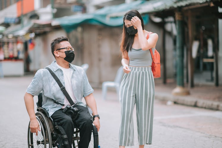 asian chinese male with disability on wheelchair crossing road with his friends in kuala lumpur