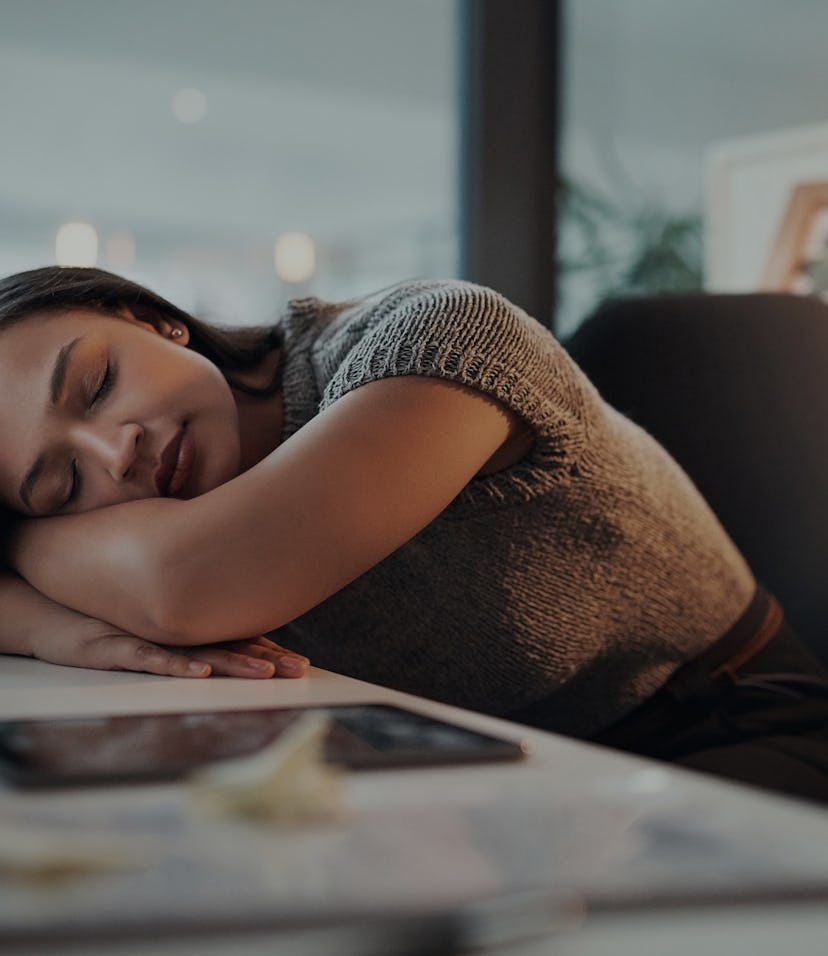 Shot of a young businesswoman lying with her head down on a desk in an office at night