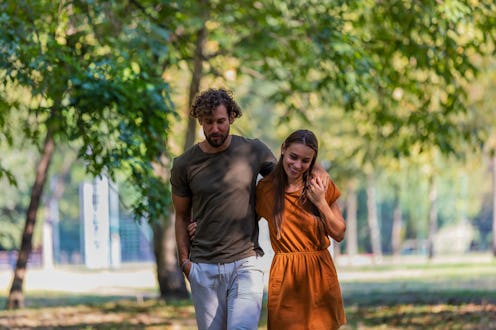 Portrait of Cheerful Young Couple who is Hugging Each Other in the Park Path and Having a Nice Conve...
