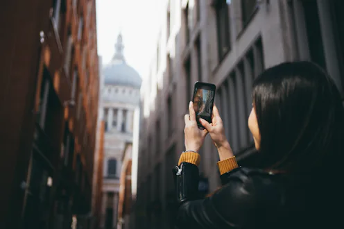 Asian cheerful woman taking a picture with her smartphone in London city.