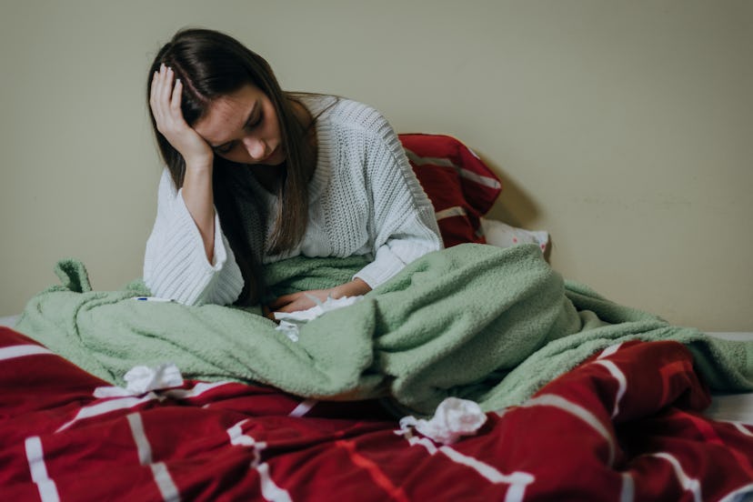 Woman sick in bed, covered with blanket