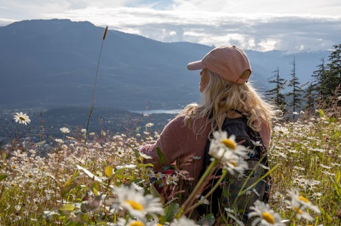 She sits among wildflowers and looks off to distant Canadian Rocky Mountains