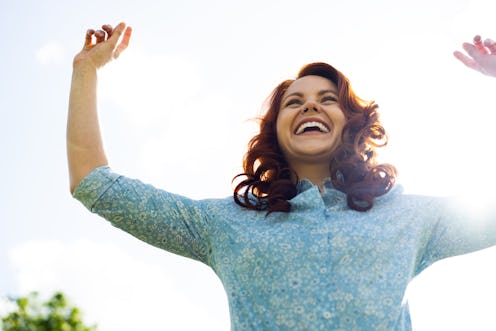 Woman jumping in air with her arms up whilst smiling