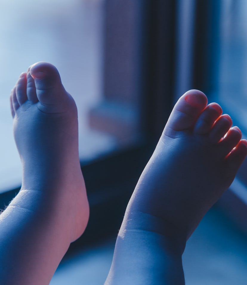 Boy's feet illuminated by light comming from balcony