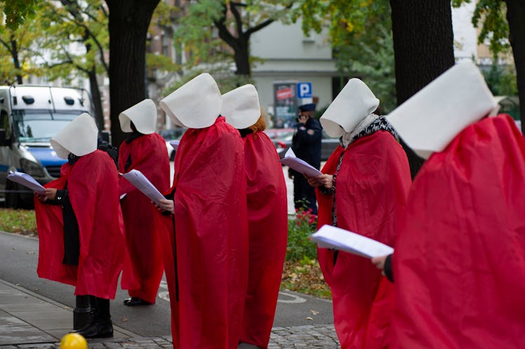 Woman's right activists wearing protective face masks are dressed as the Handmaids from the dystopia...