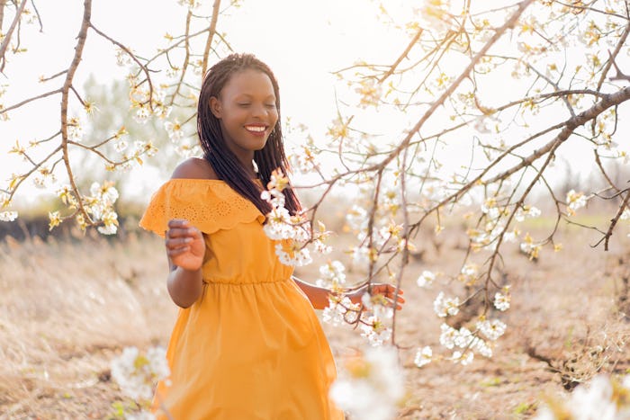 Young African woman enjoying her pregnancy at the orchard in bloom.