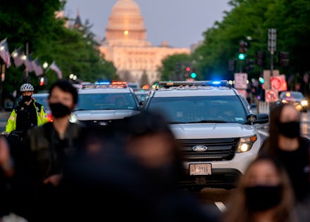 WASHINGTON, DC - APRIL 23: Police cars follow behind demonstrators during a protest on April 23, 202...