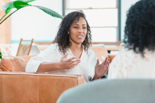 A mid adult woman gestures during a counseling session with an unrecognizable mental health professi...