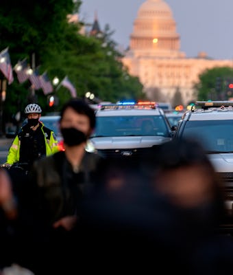 WASHINGTON, DC - APRIL 23: Police cars follow behind demonstrators during a protest on April 23, 202...