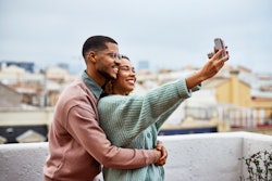 Smiling young woman taking selfie with boyfriend at building terrace. Cancer and Virgo compatibility...