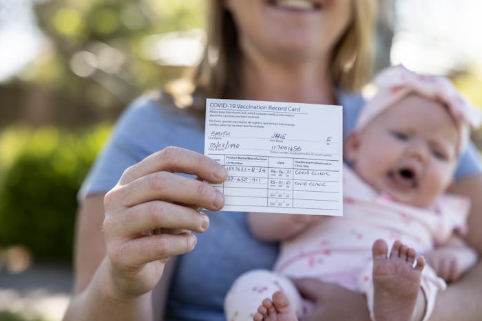 A mother with a proof of Vaccination card and her new born baby girl.