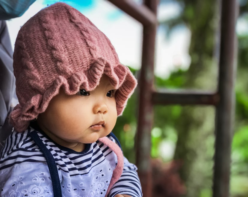 Close up of a baby wearing a pink knit beanie, in a story about Capricorn girl names.