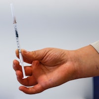 A medical worker holds up a syringe filled with the Comirnaty vaccine made by Pfizer-Biontech agains...