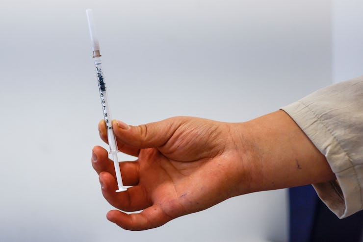 A medical worker holds up a syringe filled with the Comirnaty vaccine made by Pfizer-Biontech agains...