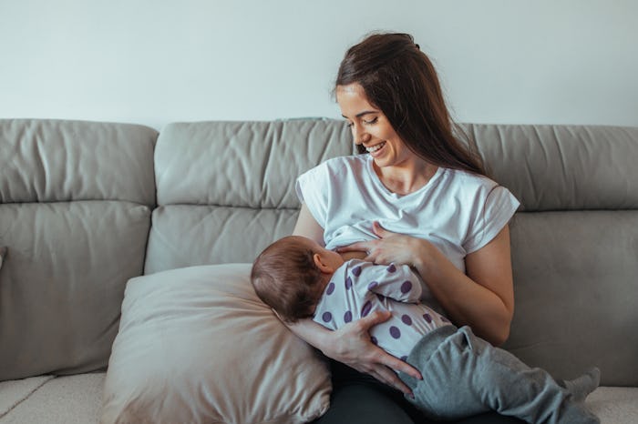 Portrait of smiling young mother breastfeeding her baby.