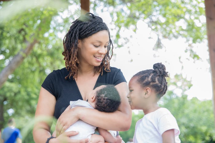 Mother breastfeeding infant son and sitting with toddler daughter