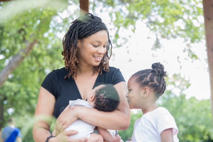 Mother breastfeeding infant son and sitting with toddler daughter