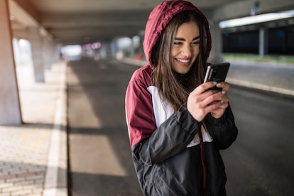 Joyful young athletic woman using phone and laughing.