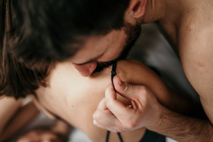 Photo of a handsome guy with a beard kissing a sholder and moving stripe of his beautiful partner wh...
