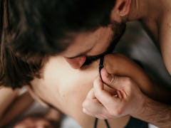 Photo of a handsome guy with a beard kissing a sholder and moving stripe of his beautiful partner wh...