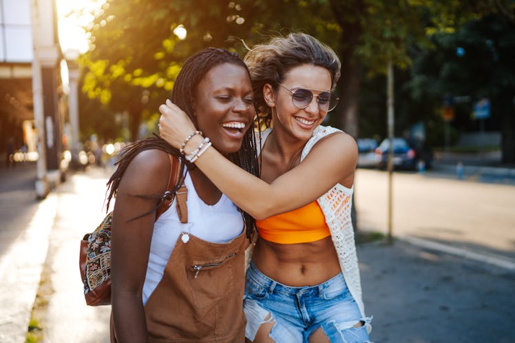 Happy young multi ethnic lesbian couple hugging and walking in the city