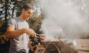 Handsome man preparing meat on old fashioned brick barbecue