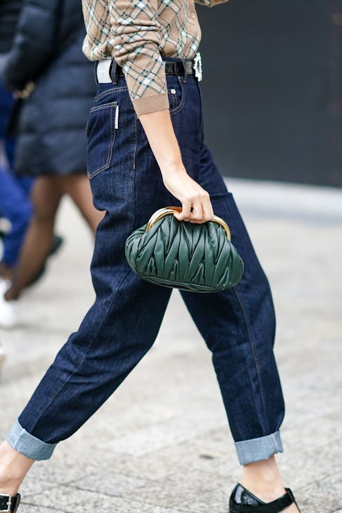 PARIS, FRANCE - OCTOBER 06: A guest wears a green woven leather Miu Miu bag, blue hem jeans, outside...