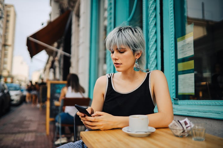 Young pretty woman sitting and texting in the street café, Buenos Aires, Argentina.