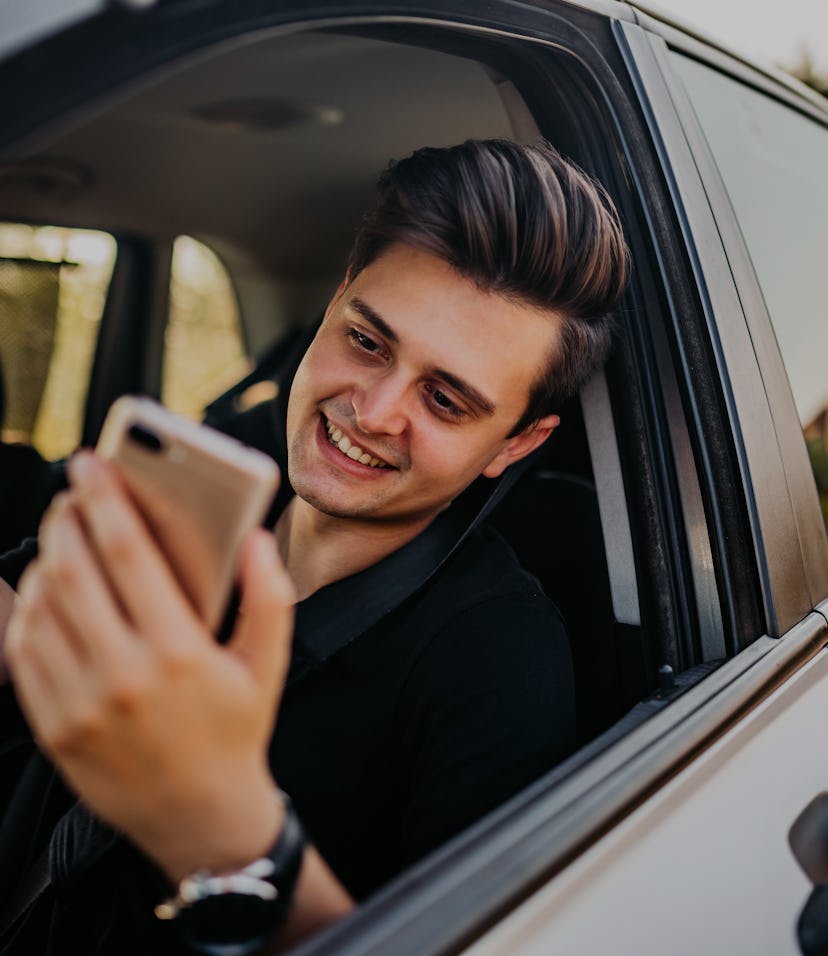 Young, handsome man pulled over with his car and making video call on phone.