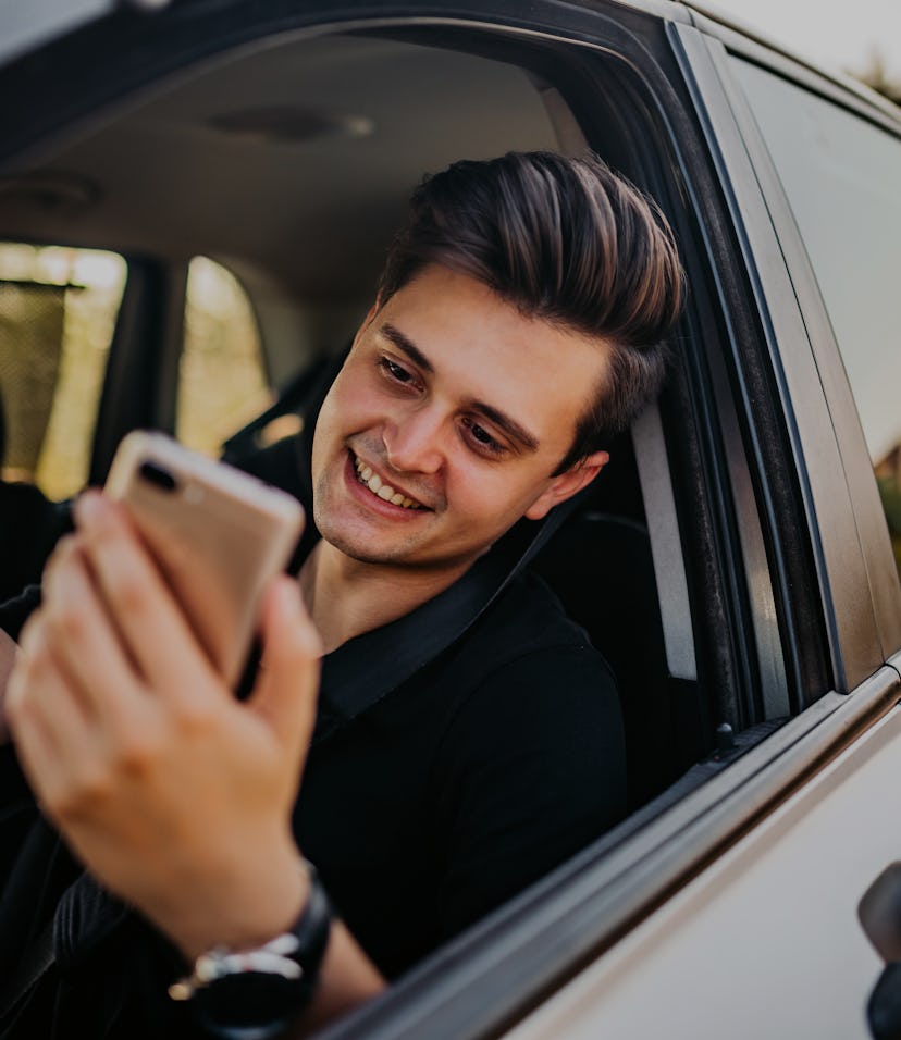 Young, handsome man pulled over with his car  and making video call on phone.
