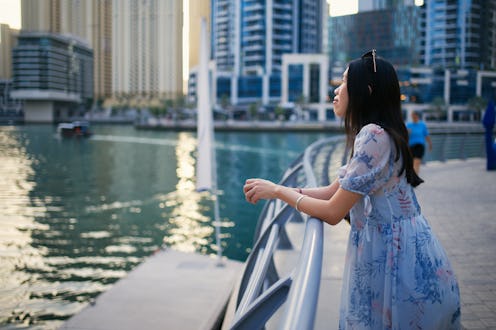 Woman enjoying scenery of modern architecture by the promenade of Dubai Marina in United Arab Emirat...