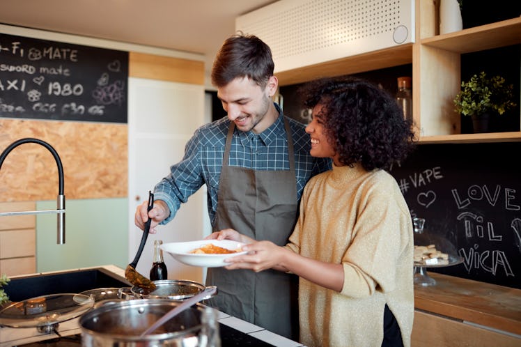A cute couple makes pasta in the kitchen together.