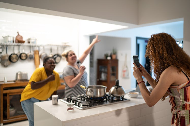 One friend films two others with their arms wide to recreate TikTok's copy the shape challenge at ho...